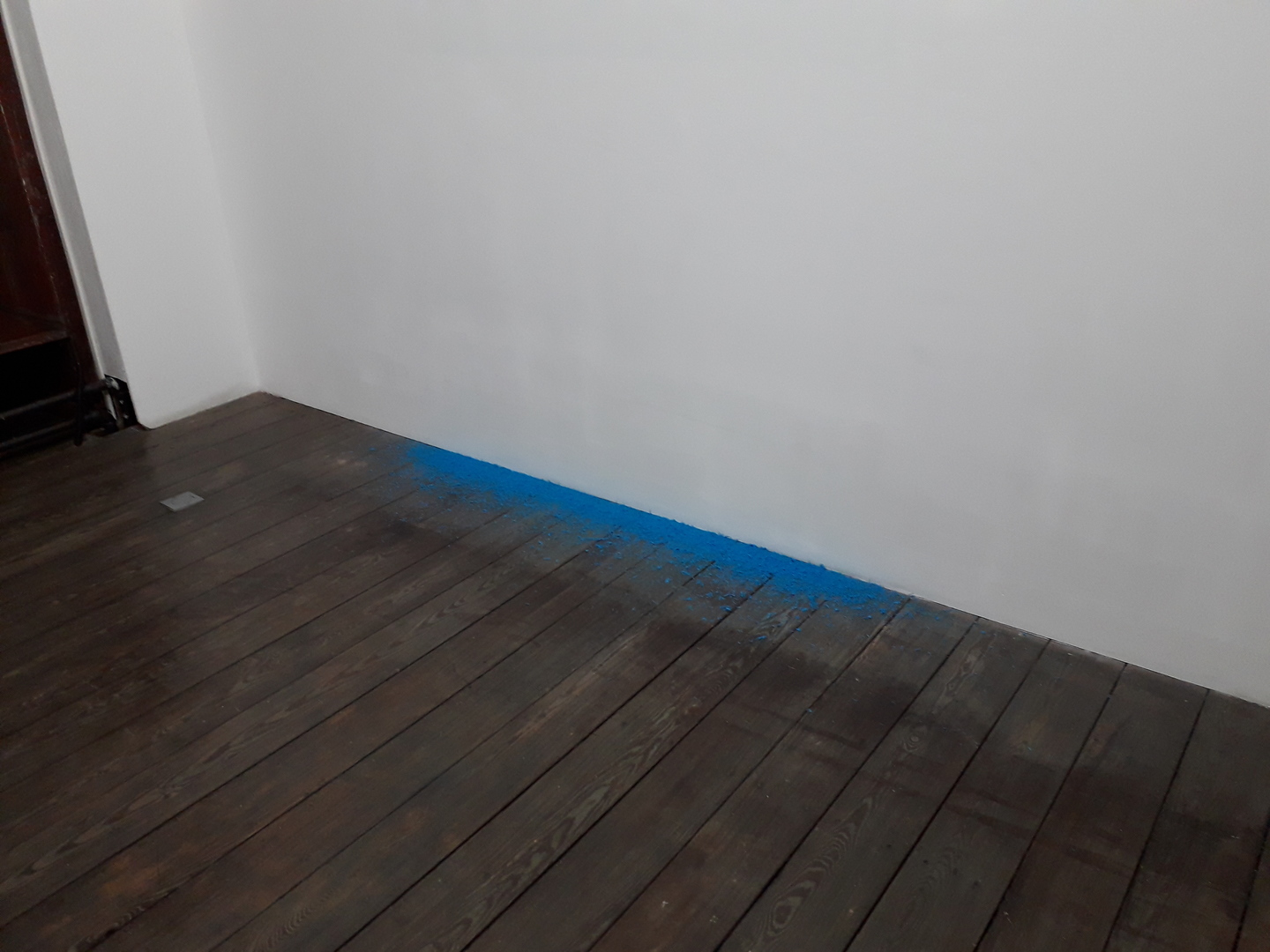 Image 1 : Poussière de craie bleue au sol au pied d'un mur