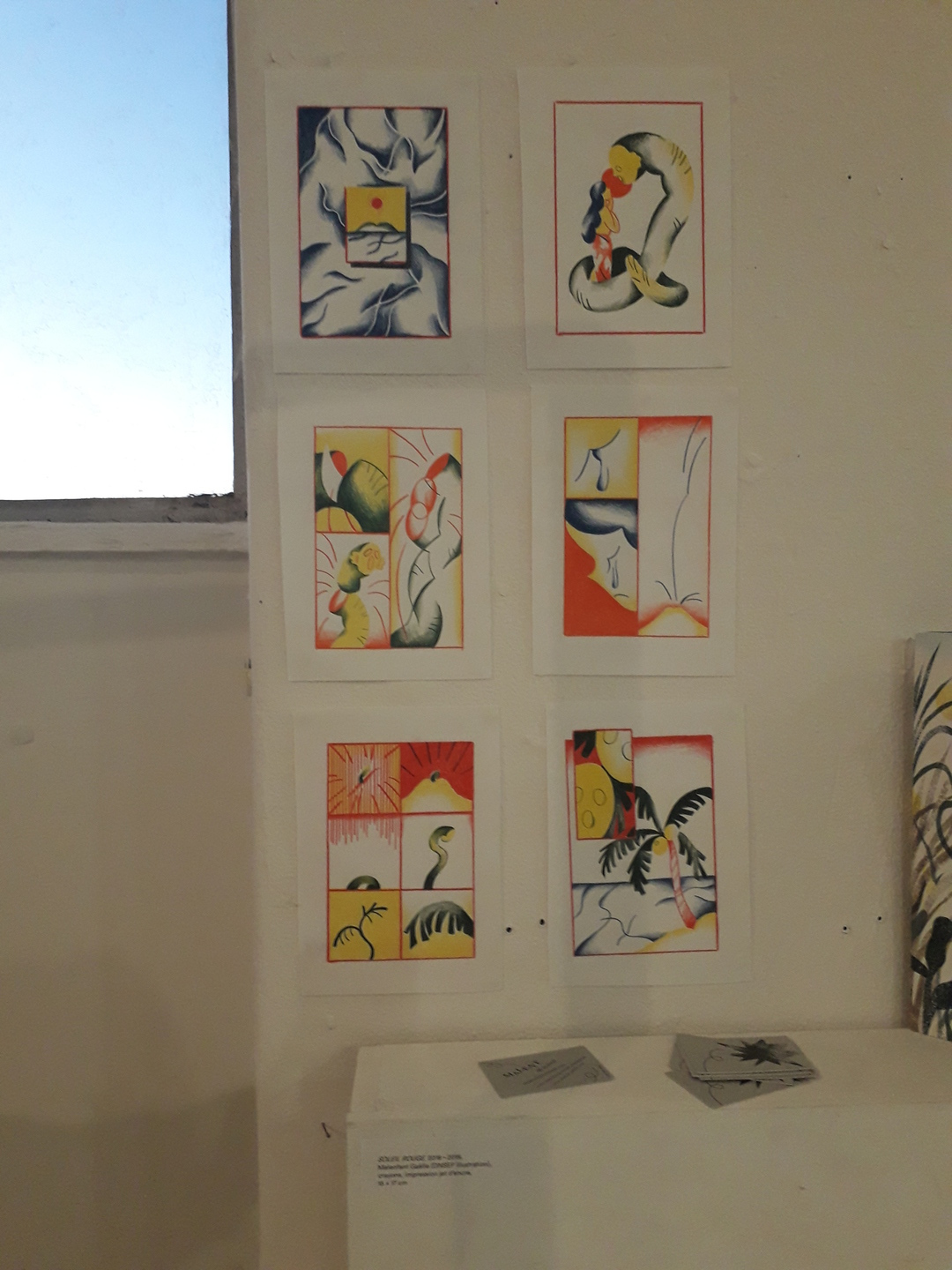 Image 2 : Illustrations à dominante orange, jaune et vert accrochées au mur