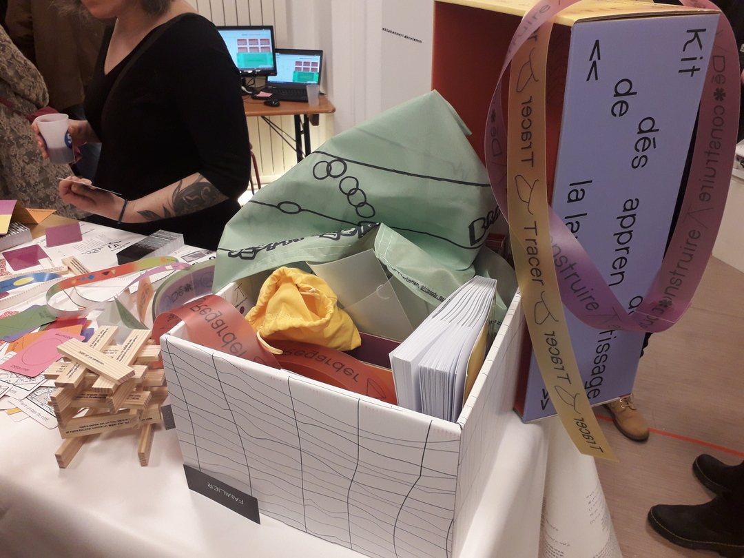 “French Unlearning Kit” displayed on a table, featuring, among other items, cards, booklets, and strips of colored paper