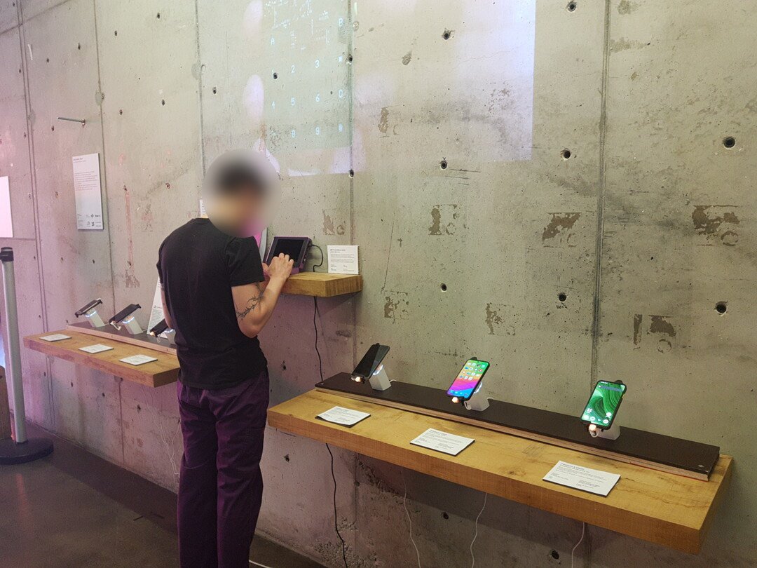 Opposite view of the exhibition, showing the projection, the Fairphones and the MNT mini PC