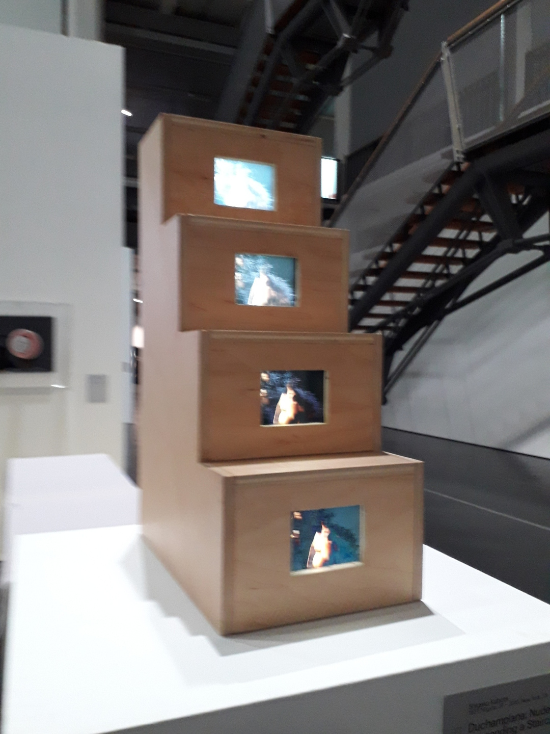 Petit escalier en bois avec un écran diffusant les étapes d'une vidéo sur chaque marche (vue 2)