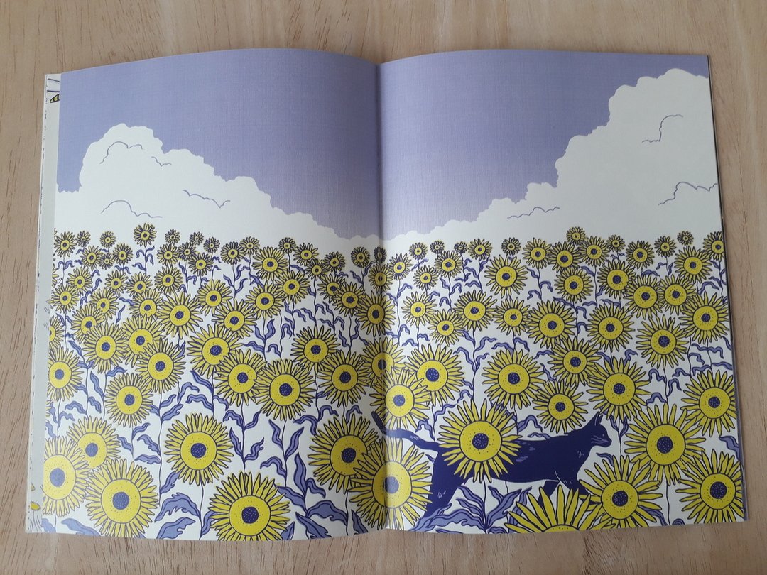 Double page d'un livre représentant un chat traversant un champ de tournesols