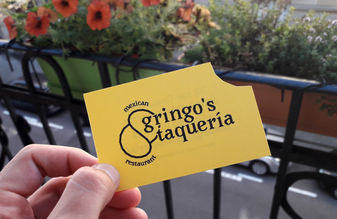 Photographie d'une carte de visite pour le restaurant de spécialités mexicaines Gringo's Taqueria avec du texte noir sur fond jaune