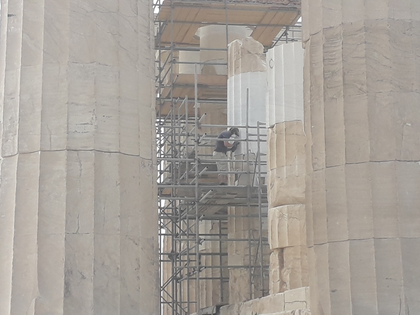 Ouvrier sur un échaffaudage entrain de restaurer des colonnes