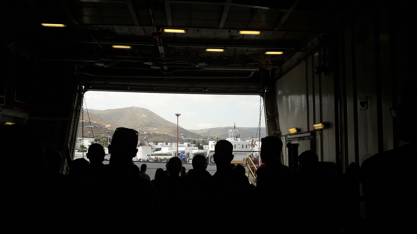 Porte d'un ferry sur le point de s'ouvrir avec des passager⸱ère⸱s s'apprêtant à descendre sur la terre ferme