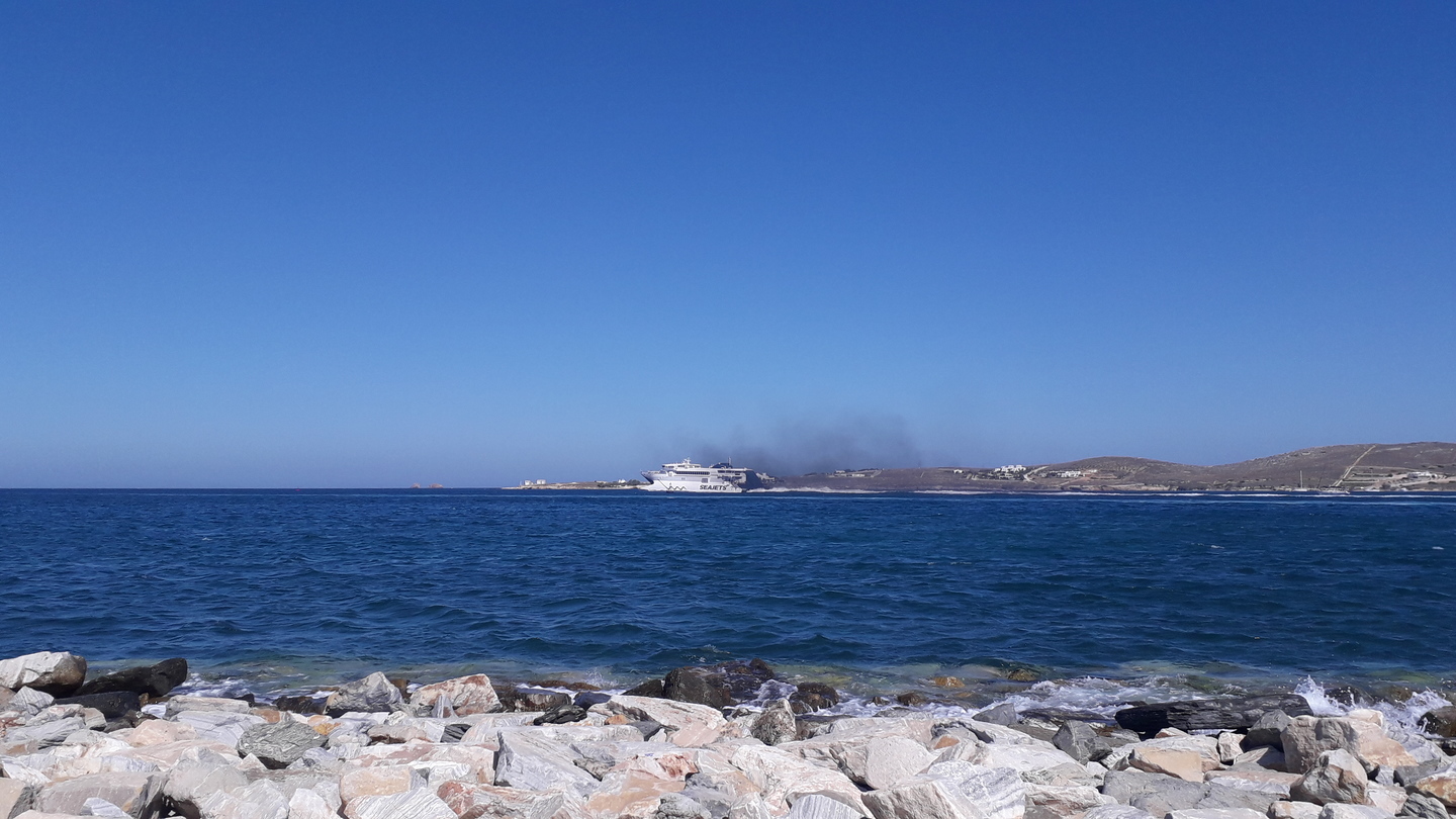 Vue de mer avec un bateau et de la fumée noire qui en émane
