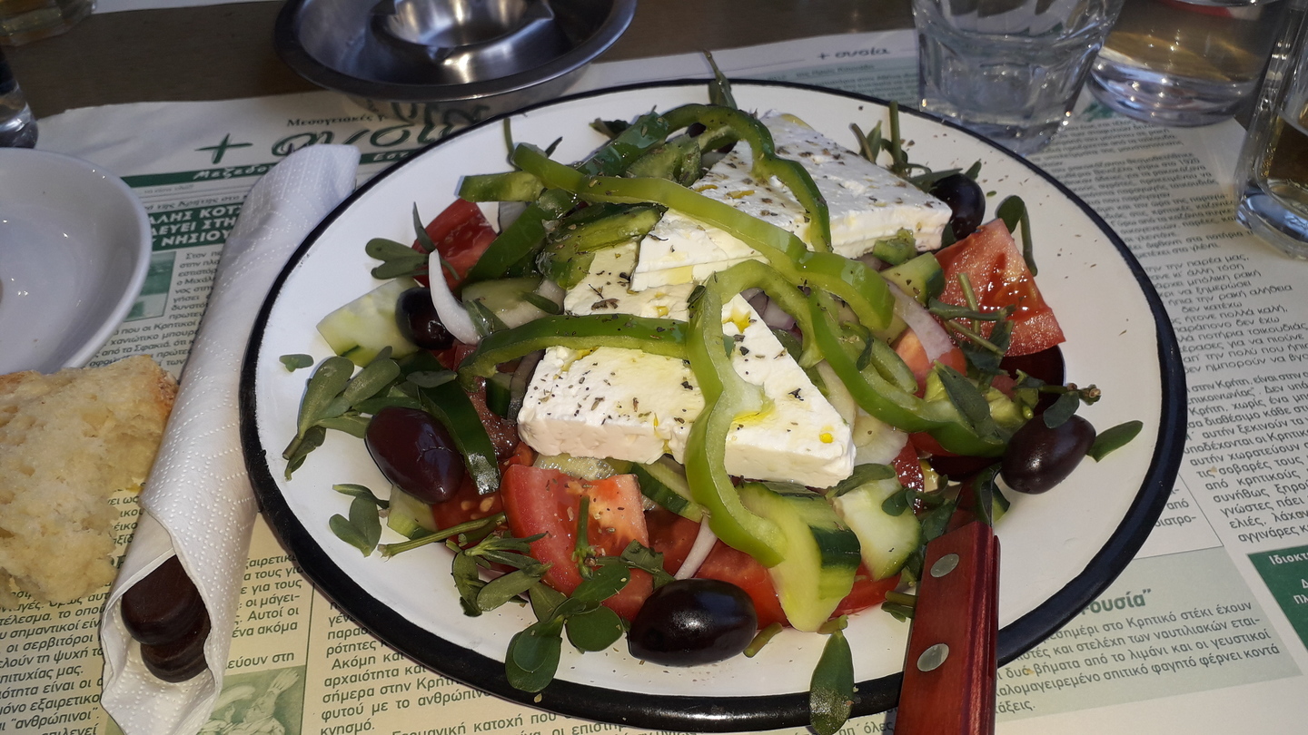 Salade composée avec blocs de feta, lanières de poivrons, olives, tomates, concombres et aromates